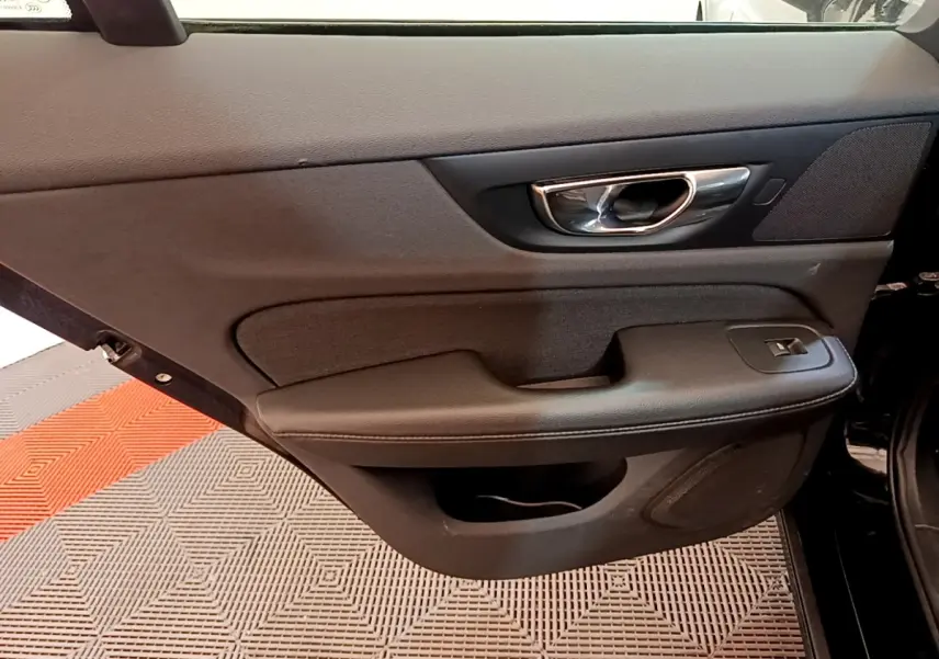Vue intérieure du panneau de porte avant droit noir du Volvo V60 D3 AdBlue 2020 avec poignée chromée et commande de vitre électrique.