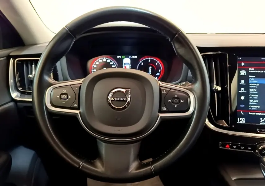 Vue centrée sur le volant en cuir noir de la Volvo V60 2020 avec tableau de bord numérique et écran tactile latéral.