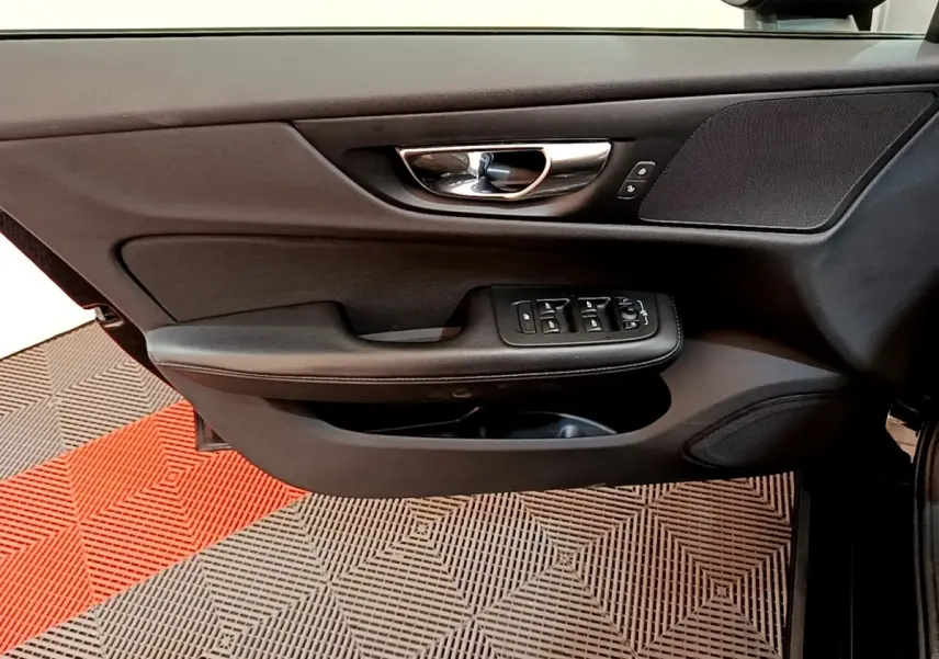 Vue intérieure sur la porte avant gauche noire d'une Volvo V60 2020 avec commandes électriques et poignée chrome.
