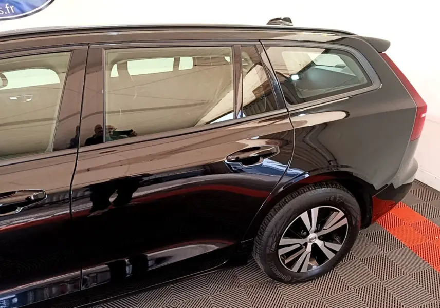 Vue latérale droite d'un Volvo V60 noir, mettant en valeur la porte arrière et la roue arrière avec jante bicolore.