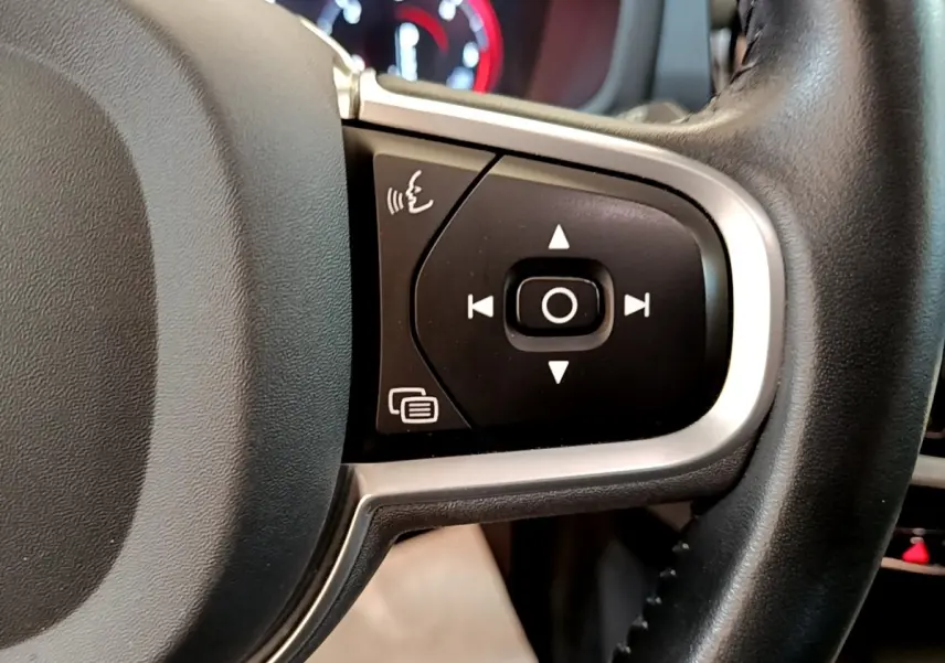 Gros plan sur les commandes multifonctions à droite du volant cuir noir d’un Volvo V60 2020, tableau de bord en arrière-plan flou.