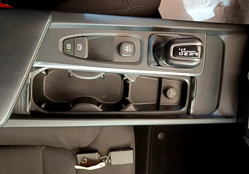 Vue plongeante sur la console centrale noire du Volvo V60 2020, montrant levier de vitesse automatique et bouton start/stop.