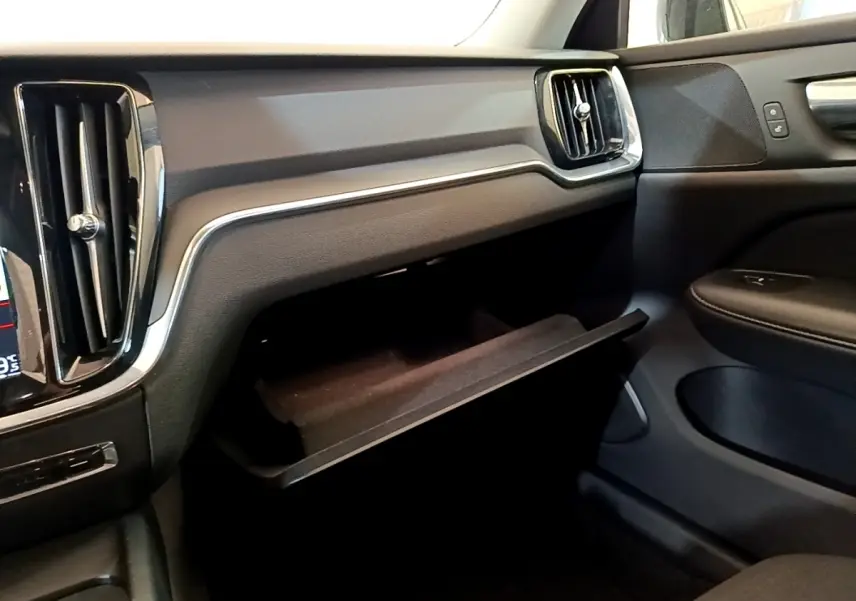 Intérieur noir de la Volvo V60 2020, vue côté passager avec boîte à gants ouverte et aérateurs rectangulaires.