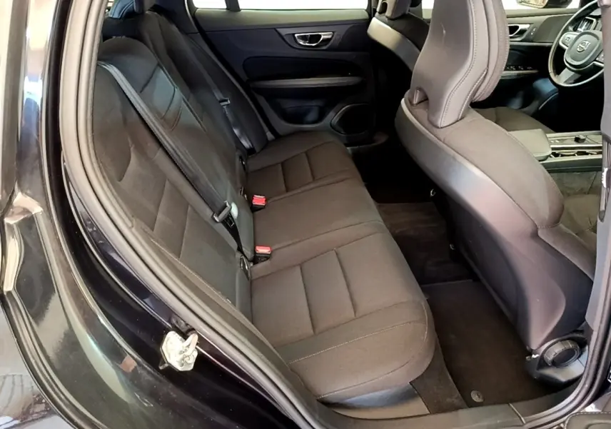 Vue intérieure côté gauche montrant la banquette arrière noire et l'avant avec le volant d'une Volvo V60 D3 Business 2020.
