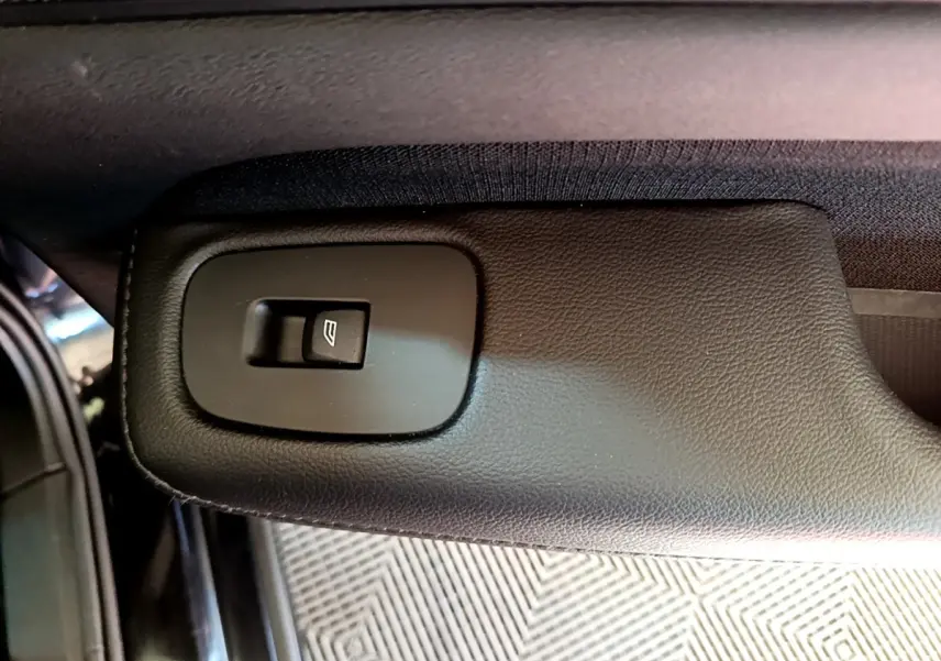 Bouton de commande de lève-vitre sur la portière intérieure noire d'une Volvo V60 D3 Business 2020.