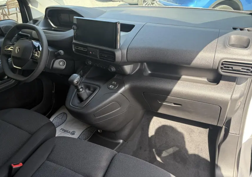Vue intérieure côté passager du Peugeot Partner 2026, montrant tableau de bord noir avec écran tactile et levier de vitesses manuel.