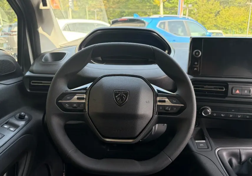 Vue intérieure centrée sur le volant cuir multifonctions noir du Peugeot Partner 2026 avec tableau de bord et écran tactile.