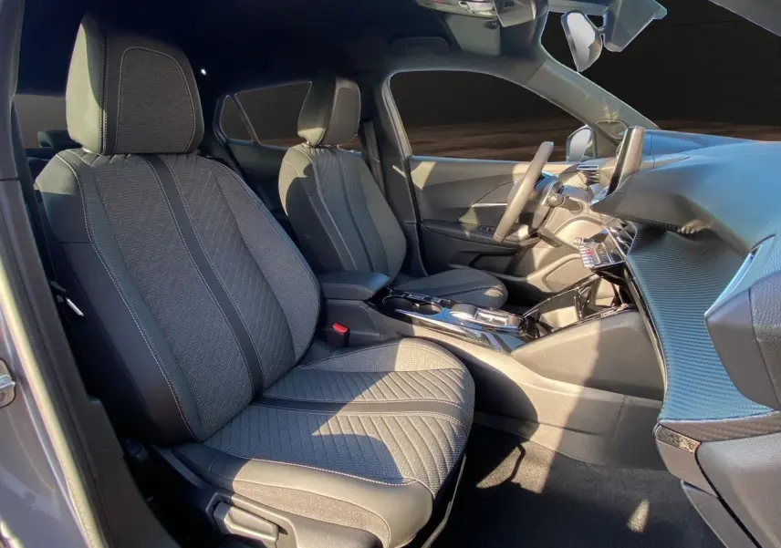 Intérieur avant du Peugeot 2008 2024 gris Artense, sièges tissu noir et console centrale brillante vue côté droit.