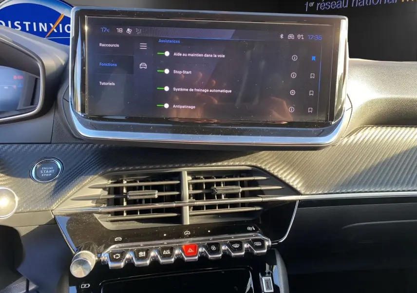 Tableau de bord de Peugeot 2008 2024 avec écran tactile affichant les aides à la conduite, finition noire et détails carbone.