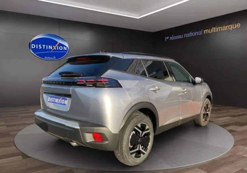 Vue 3/4 arrière droit d'un Peugeot 2008 gris Artense avec jantes noires et toit noir dans un showroom.