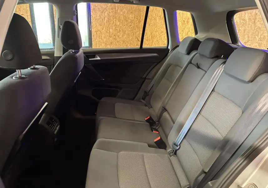 Vue latérale intérieure montrant les sièges arrière en tissu gris noir du Volkswagen Golf Sportsvan 2019.