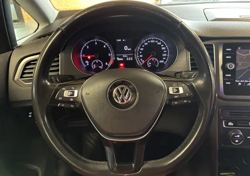 Vue rapprochée du volant multifonction noir et du tableau de bord digital d'une Volkswagen Golf Sportsvan gris 2019.