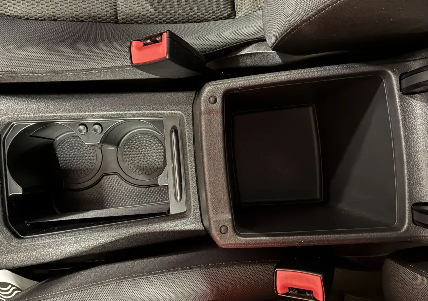 Vue plongeante sur la console centrale noire avec porte-gobelets et rangement ouvert d'une Volkswagen Golf Sportsvan gris 2019.