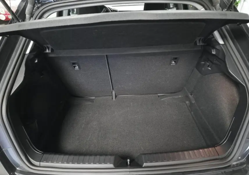 Coffre ouvert vu de l'arrière d'une Audi A1 Sportback gris Manhattan, espace de chargement vide et tapis noir.