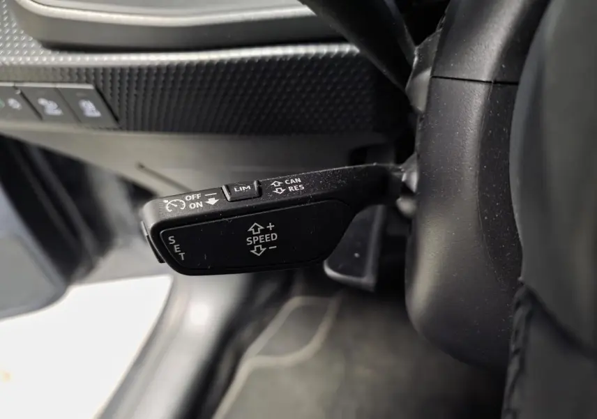 Gros plan sur la commande de régulateur de vitesse au volant cuir de l'Audi A1 Sportback gris 2024.