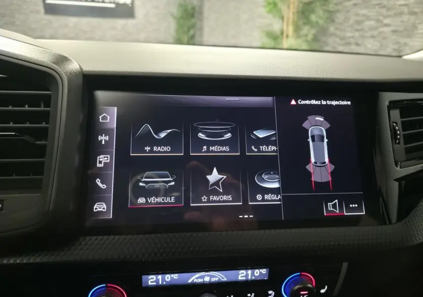 Écran tactile central de l'Audi A1 Sportback 2024 montrant l'interface multimédia et l'aide au stationnement