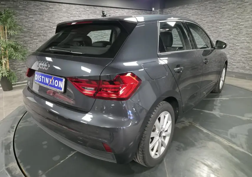 Audi A1 Sportback gris Manhattan vue 3/4 arrière droit en intérieur avec feux arrière LED et jantes argentées.