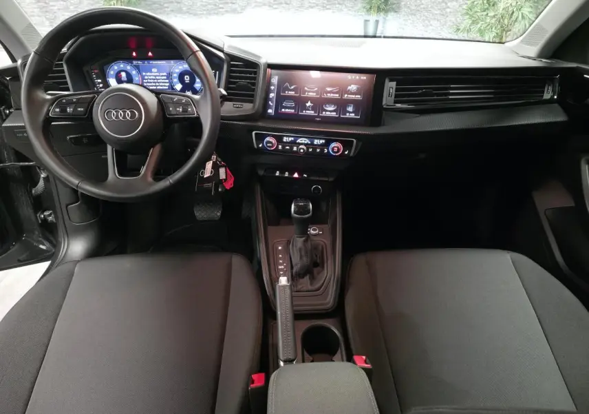 Intérieur avant d'Audi A1 Sportback 2024, vue du conducteur, sièges tissu gris et tableau de bord numérique.