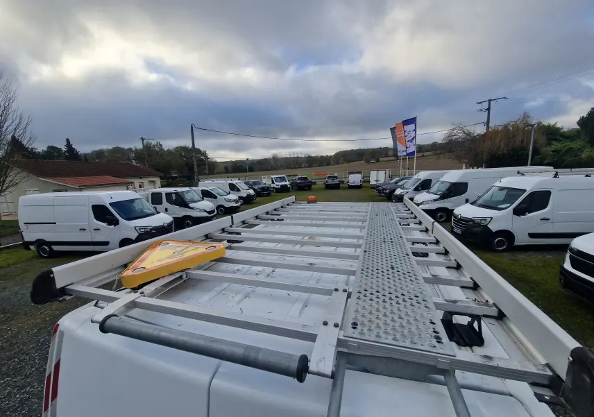 Vue en plongée sur la galerie blanche d'un Renault Master blanc 2020, avec un panneau triangulaire jaune posé dessus.