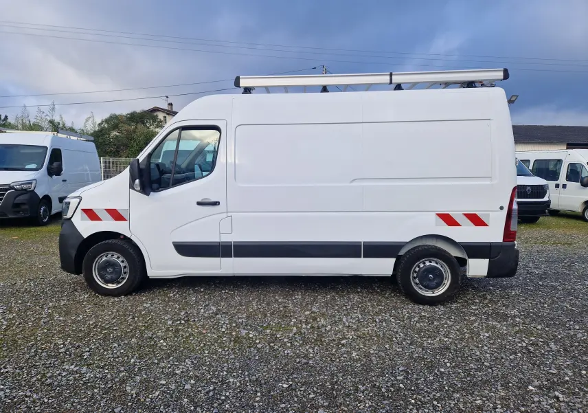 Profil côté gauche d’un Renault Master blanc 2020 avec galerie de toit et bandes réfléchissantes rouges.