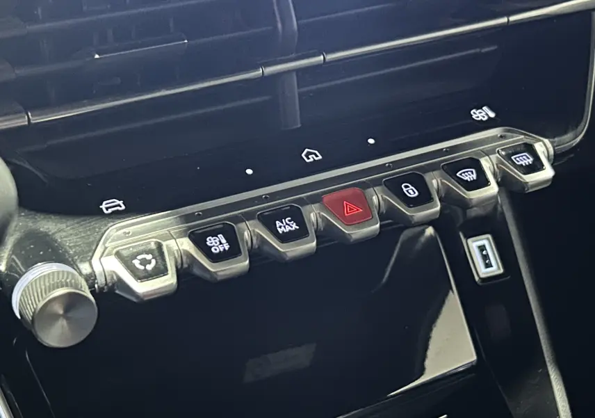 Gros plan sur la rangée de boutons de commande du tableau de bord du Peugeot 2008 Allure Hybrid 145, finition noire brillante.