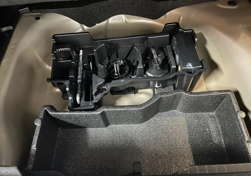 Vue plongeante sur le rangement sous le plancher de coffre du Peugeot 2008 Allure Hybrid 145, compartiment noir et beige.