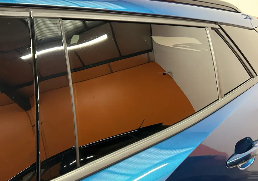 Vue latérale droite sur la porte arrière d’un Peugeot 2008 Allure Hybrid 145 bleu Obsession avec vitres teintées.