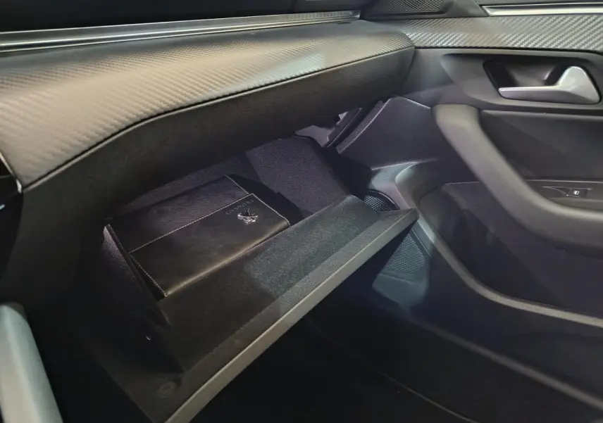 Vue intérieure côté passager du coffre à gants ouvert d’une Peugeot 508 gris clair avec manuel de bord visible.