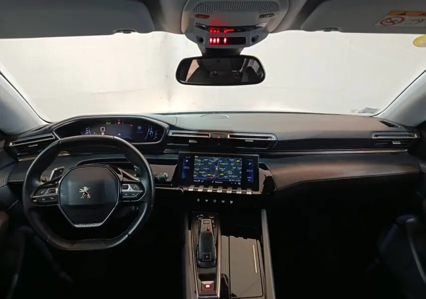 Vue intérieure avant du tableau de bord noir et volant cuir de la Peugeot 508 gris clair avec écran tactile central et affichage numérique.
