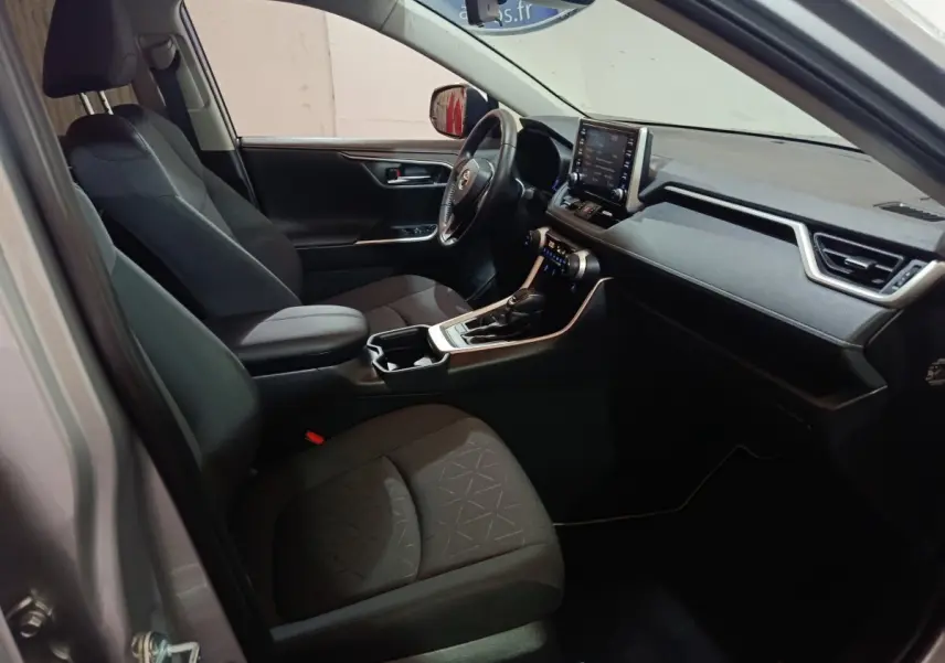 Vue intérieure côté conducteur du Toyota RAV4 hybride 2021, sièges noirs et tableau de bord avec écran tactile central.