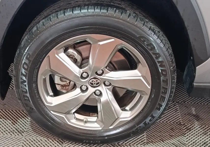 Gros plan sur la roue avant droite du Toyota RAV4 hybride, jante alliage argentée avec logo Toyota au centre.