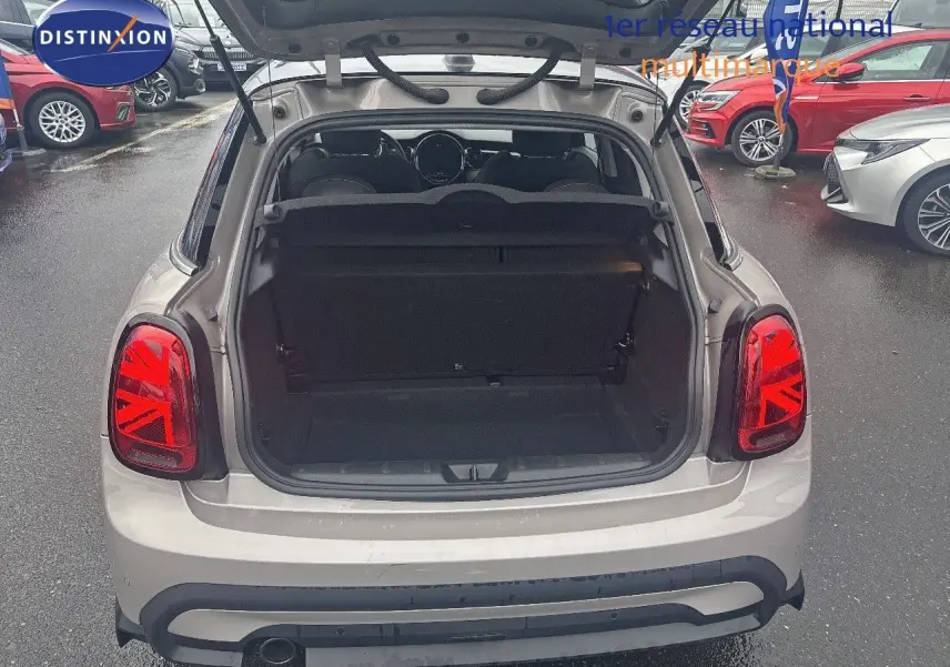 Vue arrière ouverte d'une MINI 1.5 136CH STEPTRONIC Rooftop Grey Metal, coffre vide et feux arrière Union Jack rouges visibles.