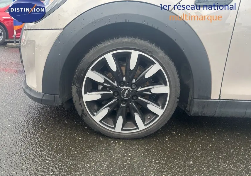 Gros plan sur la roue avant gauche d'une MINI 2023 couleur rooftop grey metal avec jante bi-ton noire et argent.