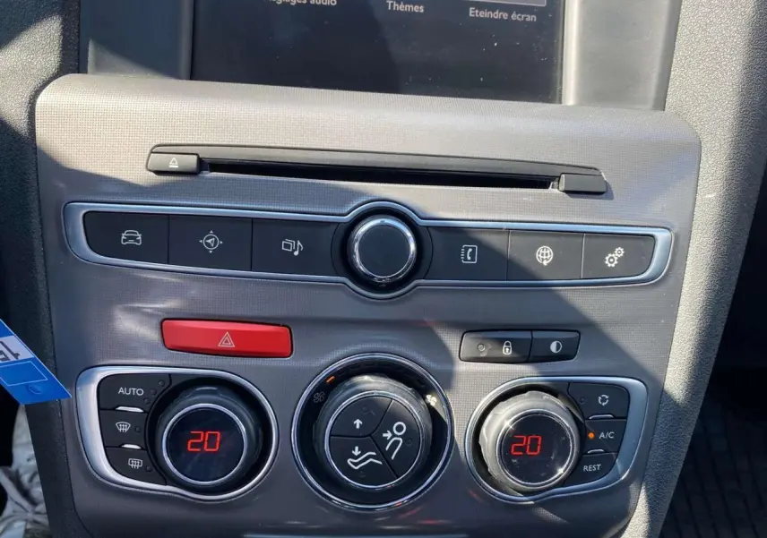 Vue rapprochée de la console centrale grise d'une Citroën C4 rouge 2015, avec commandes climatisation à 20°C.