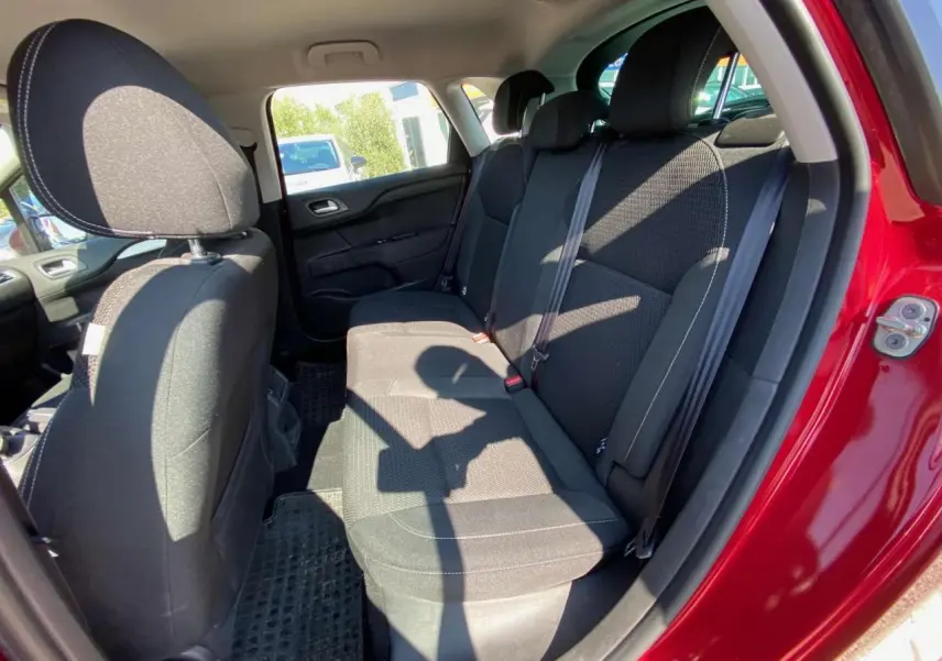 Vue intérieure de la banquette arrière noire d'une Citroën C4 rouge 2015, porte arrière droite ouverte.