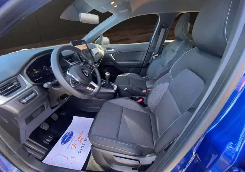 Vue intérieure côté conducteur du Renault Captur TCE 90 Evolution 2024 en bleu Iron avec toit noir, volant et tableau de bord visibles.