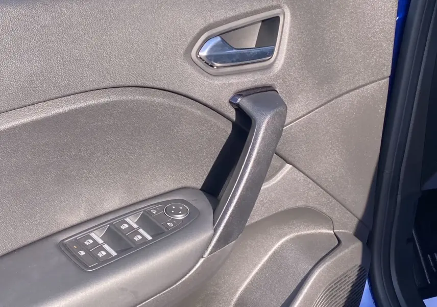 Détail de la porte avant gauche du Renault Captur 2024 bleu Iron, montrant la poignée et les commandes des vitres.