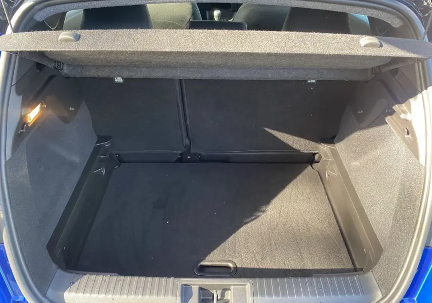 Coffre ouvert du Renault Captur TCE 90 Evolution 2024 bleu iron avec toit noir, vue arrière montrant l'espace de chargement vide.