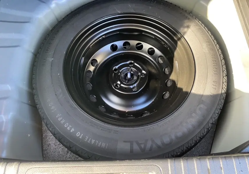 Roue de secours noire en gros plan dans le coffre d'un Renault Captur TCE 90 Evolution bleu iron toit noir 2024.