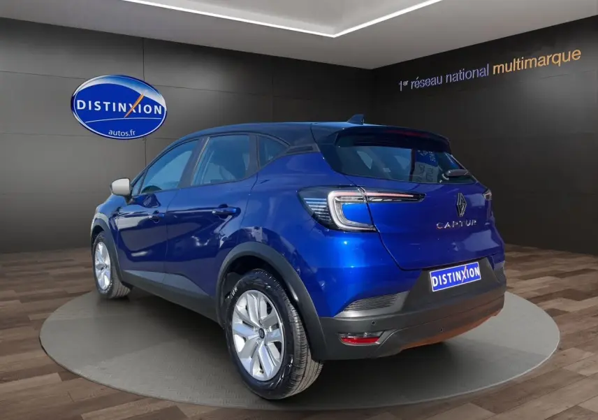 Vue 3/4 arrière droite d'un Renault Captur 2024 bleu Iron à toit noir avec caméra et jantes argentées.