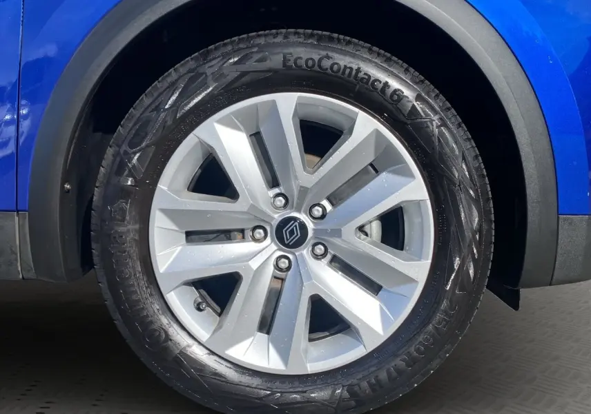 Gros plan sur la roue avant gauche d'un Renault Captur 2024 bleu Iron avec jante argentée et pneus Continental.