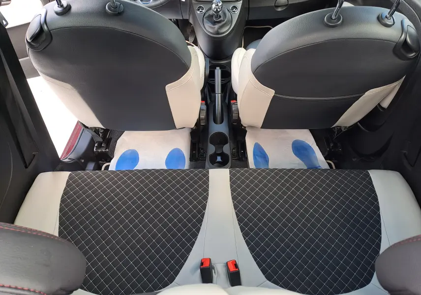Vue intérieure arrière de la Fiat 500 2020, sièges avant bicolores noir et beige, banquette arrière avec tissu à motif losanges.