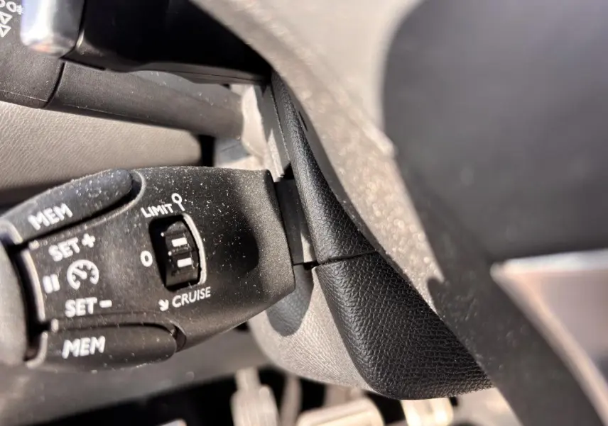 Gros plan sur la commande de régulateur de vitesse au volant d'une Peugeot 308 GT Line rouge foncé de 2016.