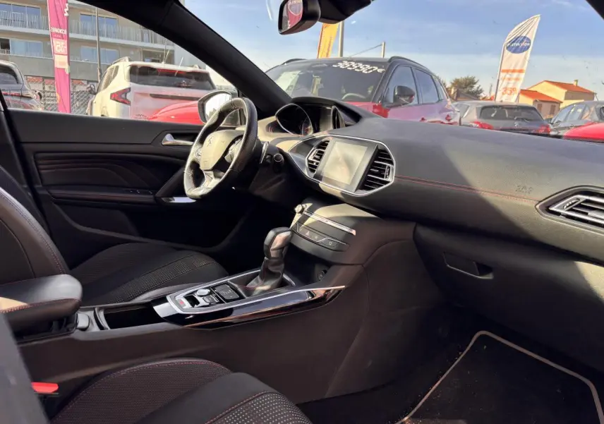 Intérieur avant droit de Peugeot 308 GT Line 2016 avec tableau de bord noir et surpiqûres rouges visibles.