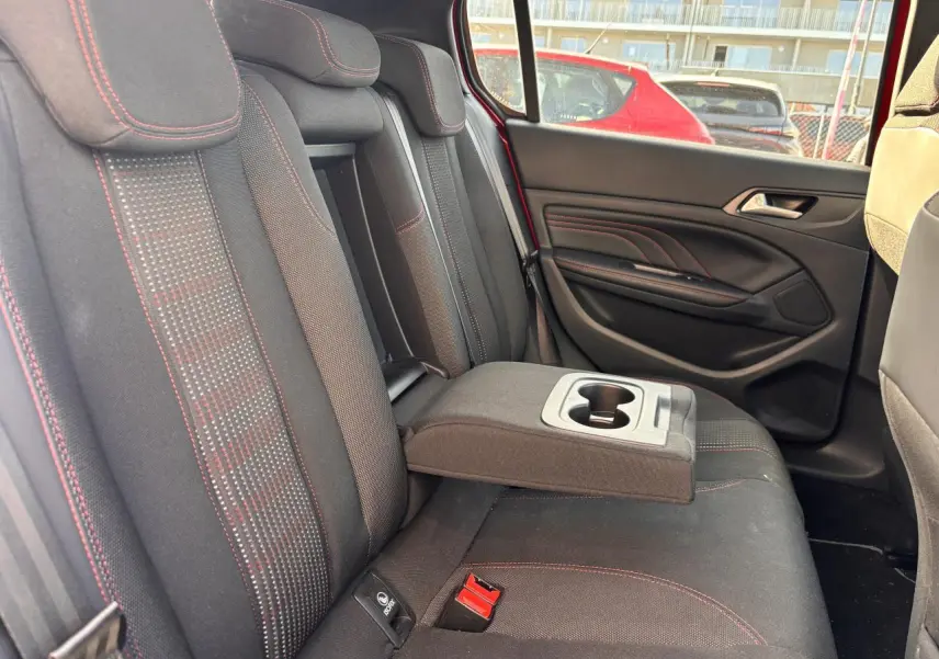 Vue côté droit de la banquette arrière noire avec surpiqûres rouges et accoudoir central déployé d'une Peugeot 308 rouge foncé.
