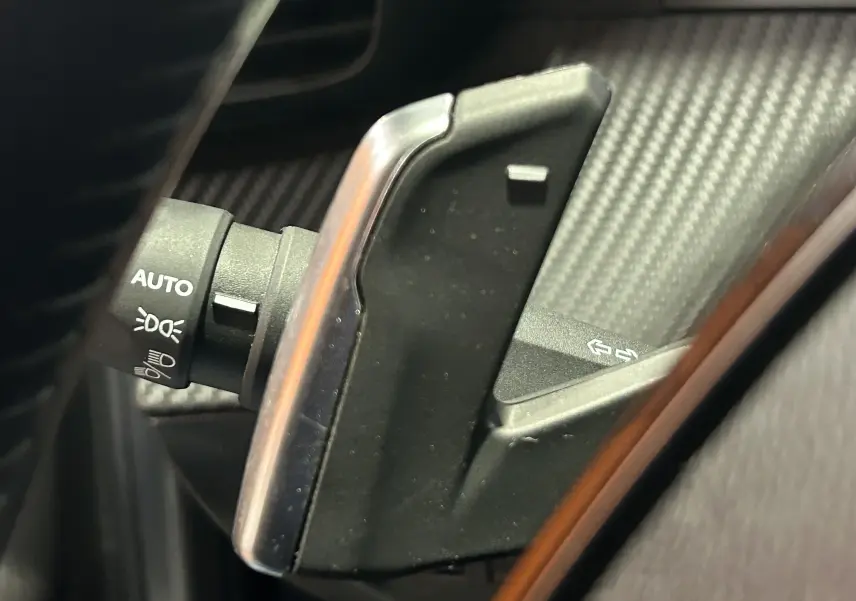 Gros plan sur la palette de changement de vitesse noire et argentée du Peugeot 2008 Allure Hybrid 145, intérieur gris foncé.