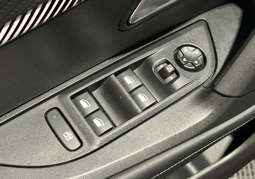 Gros plan sur les commandes de lève-vitres et réglage des rétroviseurs côté conducteur du Peugeot 2008 gris 2025.
