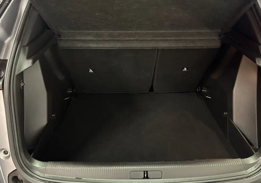 Coffre ouvert vu de l'arrière d'un Peugeot 2008 Allure Hybrid 145 gris, montrant un espace de chargement propre et spacieux.