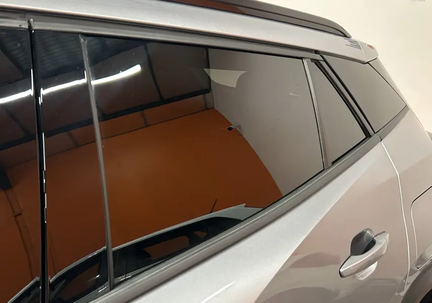 Vue latérale droite sur la partie arrière d'un Peugeot 2008 gris avec vitres teintées et poignées de porte visibles.