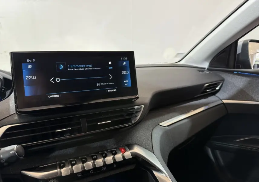 Vue intérieure côté passager du tableau de bord du Peugeot 5008 gris clair avec écran tactile central allumé.